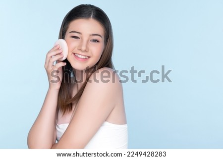 Facial cosmetic makeup concept. Portrait of young charming girl applying dry powder foundation. Beautiful girl smiling with perfect skin putting cosmetic makeup on her face.
