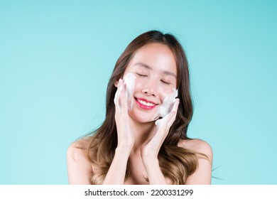 Facial Foam Cleanser Wash And Scrub, Happy Charming Young Asian Woman Applying  On Her Face On The Blue Background.