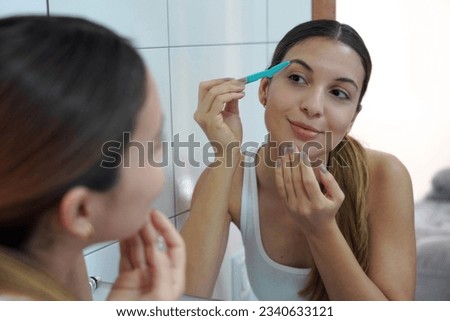 Facial hair removal. Close-up of beautiful young woman shaving her face by razor at home. Facial hair removal.