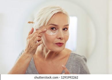 Facial mask. Nice elderly woman standing with eye patches while getting rid of fatigue signs - Powered by Shutterstock