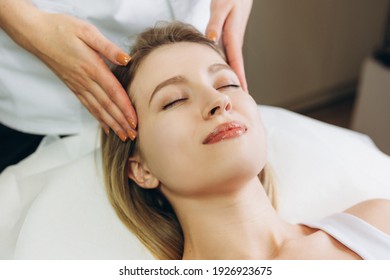 Facial massage beauty treatment. Close-up of a young woman s face lying on back, getting face lifting massage, pinch and roll technique