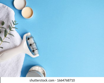 Facial Massage Roller With Towel, Cream, Little Plant On Blue Background . Concept Skincare And Beauty Routine, Care Treatment, Flatlay, Lay Out, Copyspace.