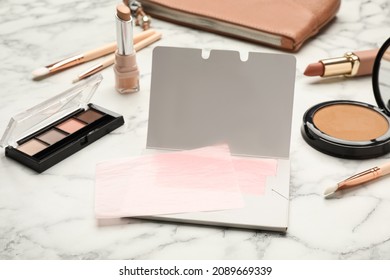 Facial oil blotting tissues and different decorative cosmetics on white marble table. Mattifying wipes