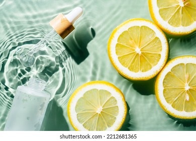 Facial Pipette Serum, Whey Beauty Product Near Fruit Citrus Lemon In Water Splashing Fresh Transparent, Flecks. Flat Lay, Top View. Summer Beach Tropical. Organic Skin Body Antiage Care In Hot Climate