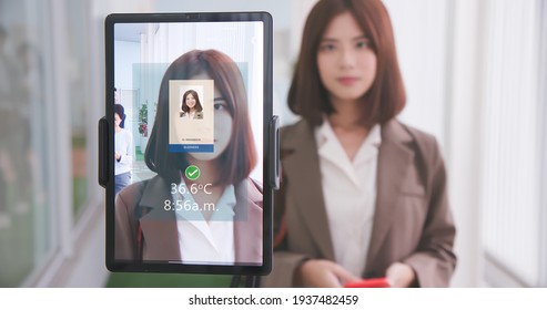 Facial Recognition Concept - Asian Businesswoman Using Face Scanner To Clock In Work And Check Body Temperature