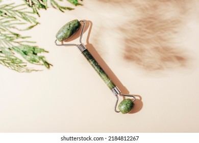 Facial Roller With Cypress Branch Shadow On Light Beige Background. Natural Cosmetics, Aromatherapy, Beauty Treatment Concept. Top View, Flat Lay.