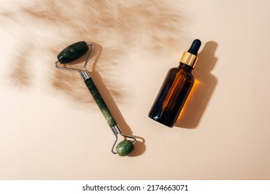 Facial Roller, Serum Bottle With Cypress Shadow On Light Beige Background. Natural Cosmetics, Aromatherapy, Beauty Treatment Concept. Top View, Flat Lay.