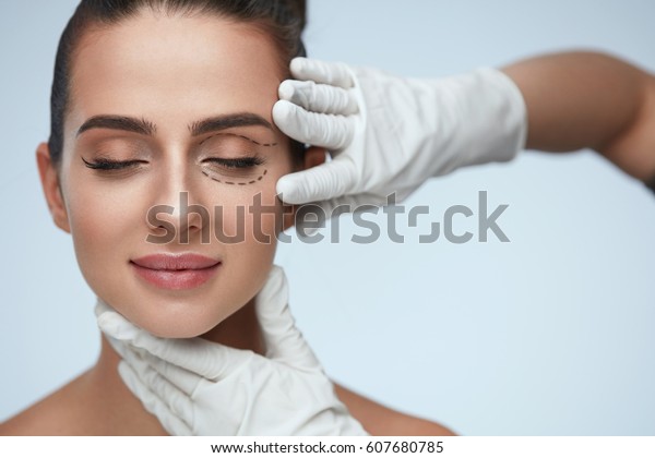 Facial Treatment. Portrait Of Beautiful Sexy\
Woman With Closed Eyes And Black Surgical Lines On Skin. Closeup Of\
Hands Touching Young Female Face. Plastic Surgery Concept. High\
Resolution