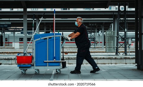 Facility Manager At Frankfurt Railway Station With Cleaning Utensiles And Covid Mask