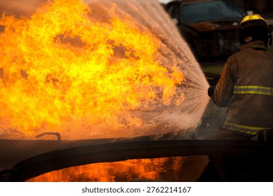 Facing intense blaze, two brave firefighters use high-pressure hose to suppress the flames. This shot captures heat and danger involved in professional fire suppression and emergency rescue operations.