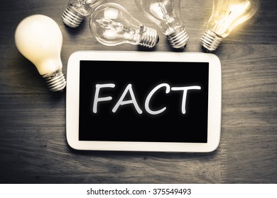 Fact topic on mobile tablet with glowing light bulbs on the table