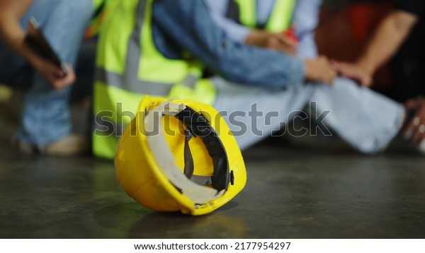 Factory Accident, Industrial accident. Warehouse\
staff having accident in the factory, industrial worker injured\
during working having pain on leg, worker helping and giving the\
injured first aid