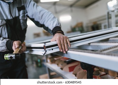 Factory for aluminum and PVC windows and doors production. Manual worker assembling PVC doors and windows. Selective focus. 