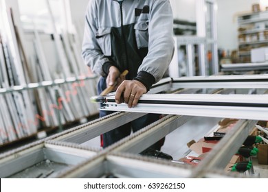 Factory for aluminum and PVC windows and doors production. Manual worker assembling PVC doors and windows. Selective focus. 