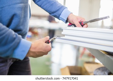 Factory for aluminum and PVC windows and doors production. Manual worker assembling PVC doors and windows. Selective focus. - Shutterstock ID 747917041