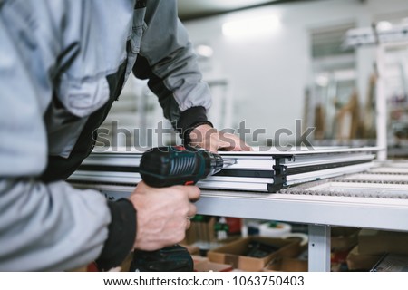 Factory for aluminum and PVC windows and doors production. Manual worker assembling PVC doors and windows. Selective focus.