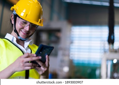 Factory Asian woman worker or technician using smartphone chatting Online Messaging with her co-worker engineer in workplace during concern about covid-19 pandemic affect industrial business ,exports - Powered by Shutterstock