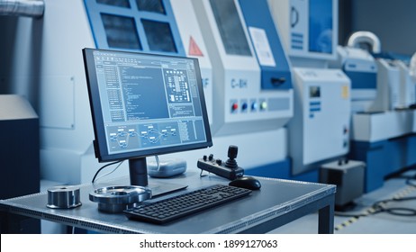 Factory Cleanroom: On the Desk Personal Computer Showing Infrastructure System Control on its Display. In Background CNC Machinery, Professionals Use Robot Arm on Production Line.