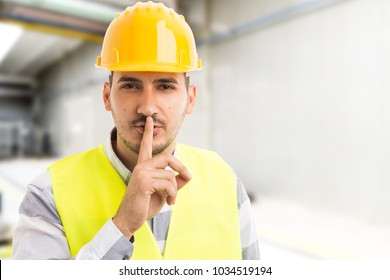 Factory or company engineer making shush silence gesture with index finger on lips