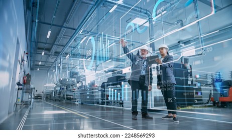 Factory Digitalization: Two Industrial Engineers Use Tablet Computer, Visualize the Wall of Big Data Statistics, Optimization of High-Tech Electronics Facility. Industry 4.0 Machinery Production