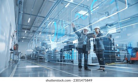Factory Digitalization: Two Industrial Engineers Use Tablet Computer, Visualize the Wall of Big Data Statistics, Optimization of High-Tech Electronics Facility. Industry 4.0 Machinery Production