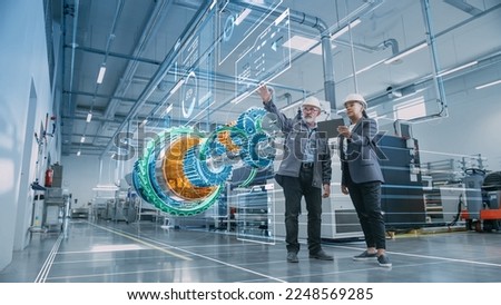 Factory Digitalization: Two Industrial Engineers Use Tablet Computer, Visualize 3D Model of Clean Green Energy Engine. Industry 4 High-Tech Electronics Facility with Machinery Manufacturing Products