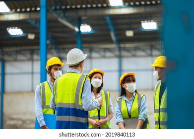 The Factory Employee Consists Of Engineers, Foreman, Technicians, And Related Department Staff. Wear A Mask, Hard Hat, And Vest. Meeting Before Starting Work Inside The Warehouse. Teamwork Concept.