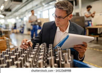 Factory engineer doing quality control inspection of manufactured steel cylinders in industrial building.  - Powered by Shutterstock