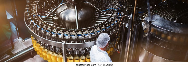 Factory engineer monitoring filled juice bottle on production line in bottle factory - Powered by Shutterstock