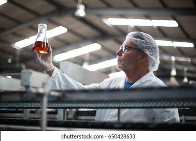 Factory engineers checking a sample of drink in drinks production plant - Powered by Shutterstock