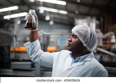 Factory engineers checking a sample of drink in drinks production plant - Powered by Shutterstock