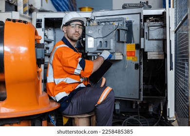 Factory engineers wear uniform and helmet are checking quality system of machines before use. Service programming production. machinery. - Shutterstock ID 2258485385