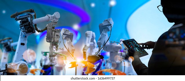 Factory Female Industrial Engineer working with automation robot arms machine in intelligent factory industrial on real time monitoring system software.Digital future manufacture.