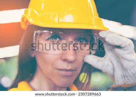 Factory female worker. Engineer  woman worker with laptop working in plant production checking and testing machine in smart factory wearing yellow hard hat safety first at mechanic factory.