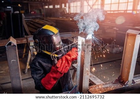 Factory industrial weld worker in workplace with spark. Professional welder erecting metal steel.