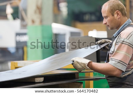 Factory Man Worker Holding Metal Sheet in Workshop during Manufacturing Process 