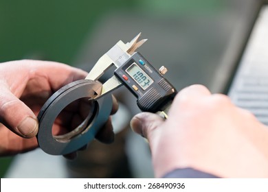 Factory man worker measuring steel detail with digital Vernier Caliper at workshop