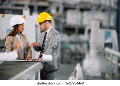 Factory manager and engineer doing inspection. Businessman and businesswoman at production line.