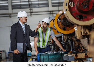 Factory manager inspecting a finished precision metal component with a production technician on an industrial manufacturing floor. Reviewing product quality before approval, the team demonstrates engineering supervision.