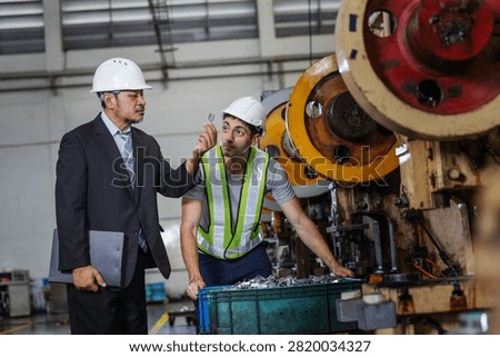 Factory manager inspecting a finished precision metal component with a production technician on an industrial manufacturing floor. Reviewing product quality before approval, the team demonstrates engineering supervision.