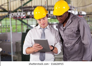 Factory Manager And Worker Looking At Tablet Computer