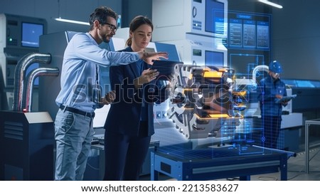 Factory Office Facility: Chief Engineer Holds Tablet Computer, Shows Augmented Reality Model of an Electric Generator to a Female Project Manager. Modern Industry 4.0 Research and Development Center.