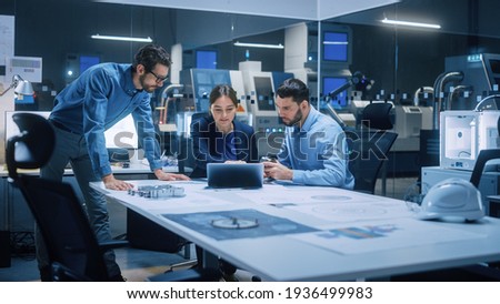 Factory Office Meeting Room: Team of Engineers Gather Around Conference Table, They Discuss Project Blueprints, Inspect Mechanism, Find Solutions, Use Laptop. Industrial Technology Factory