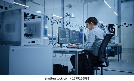 Factory Office: Portrait Of Beautiful And Confident Male Industrial Engineer Working On Computer, On Screen Industrial Electronics Design Software. High Tech Facility With CNC Machinery