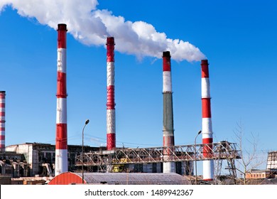 Factory Plant Smoke Stack Over Blue Sky Background. Thermal Condensing Power Plant. Energy Generation And Air Environment Pollution Industrial Scene