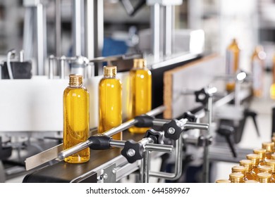 Factory  And Research Concept. Bottles With Yellow Thick Substance Standing On Manufacturing Facility Going To Be Twisted. Glass Bottles In Line On Conveyor Belt. Production Process Of Cosmetics