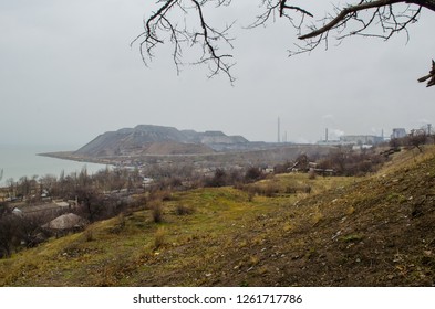 Factory And A Slag Mountain In The Distance By The Sea
