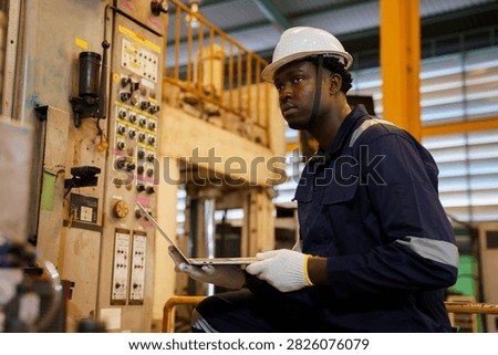 Factory supervisor conducting routine walkthrough inspection along machinery production line inside industrial plant. Technician checking equipment operational status and maintenance.
