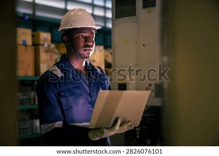 Factory supervisor conducting routine walkthrough inspection along machinery production line inside industrial plant. Technician checking equipment operational status and maintenance.