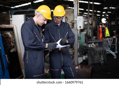 Factory technicians are discussing or planning work. They wear uniforms, safety helmets, and protective goggles. And look at the clipboard with details of the work. - Powered by Shutterstock